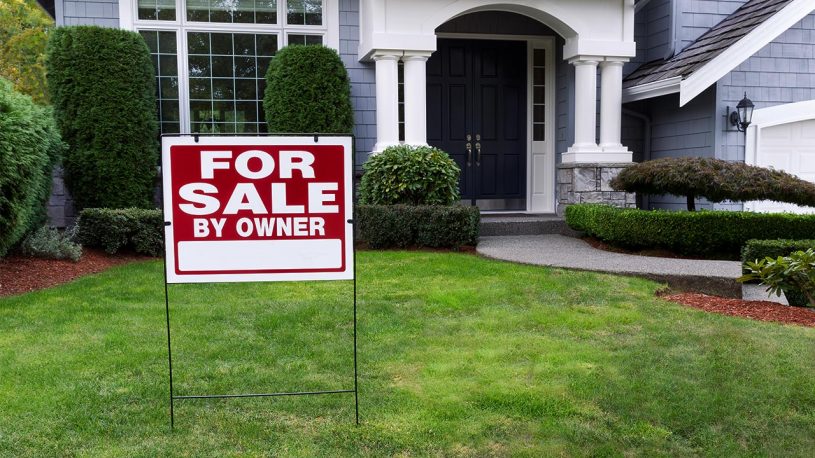 House with green grass and red for sale sign