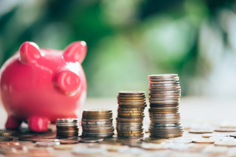 Pink piggy bank with coins stacked in front of it resembling a savings account