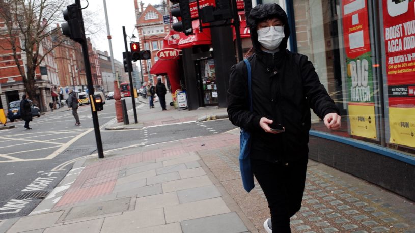 Person walking with medical mask and not using physical bank because of COVID-19