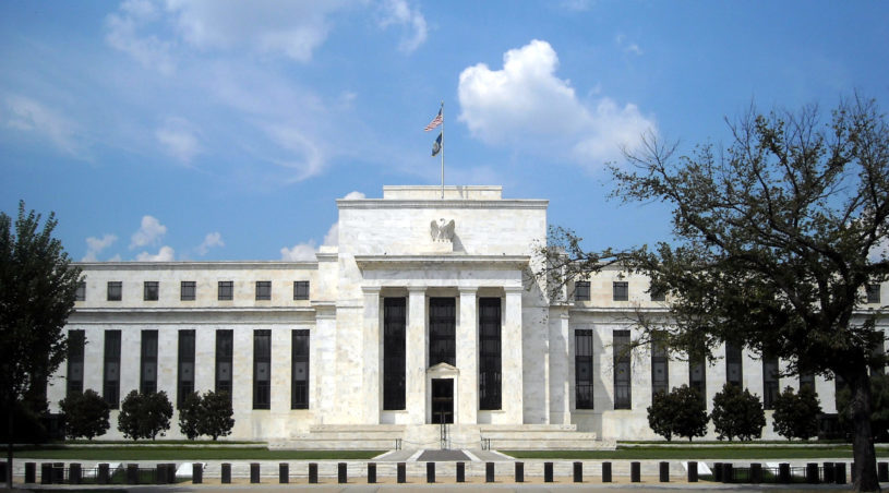 US Federal Reserve building with flag waving and blue sky in background