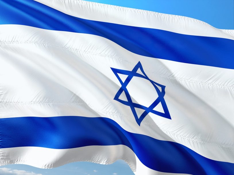 Israeli flag waving in wind with blue sky in background