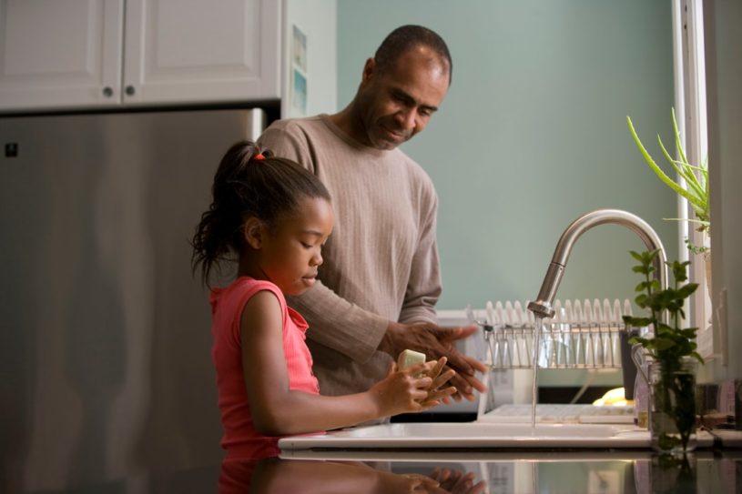 Father teaching daughter how to wash hands and also preparing for financial future with Acorns Early
