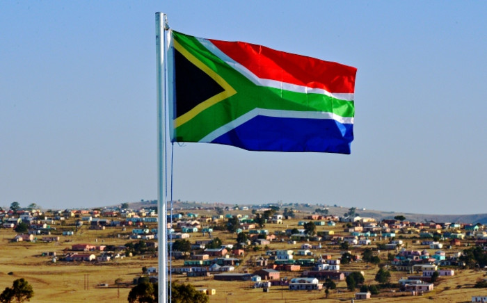 Red, blue, green, and black South African flag waving in the wind with the sky in the background