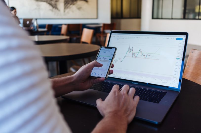 Man sitting at desk and buying stocks on phone to protect his portfolio