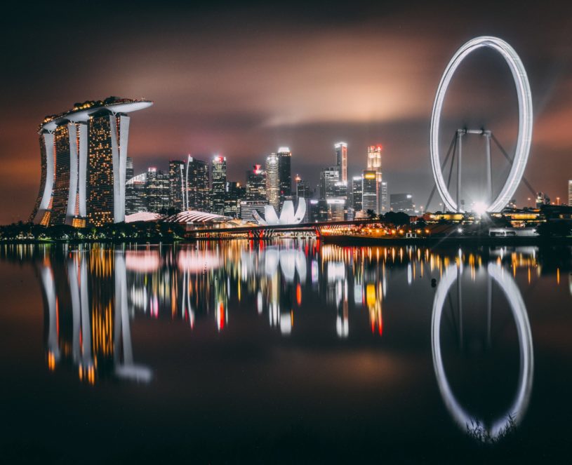 Singapore skyline with many buildings in the background and the ocean in the foreground.