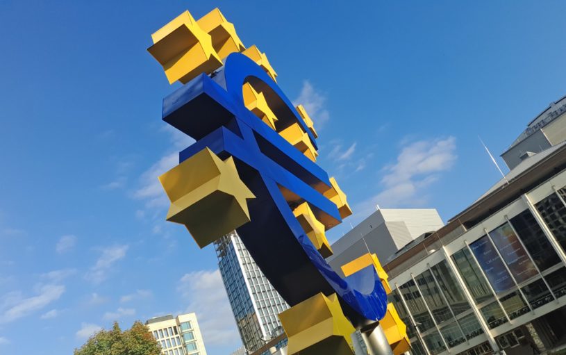 Euro sign outside in blue and yellow with blue sky in background