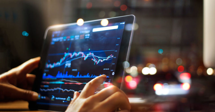 Stock trader holding an iPad and looking at the top stocks to watch this week.