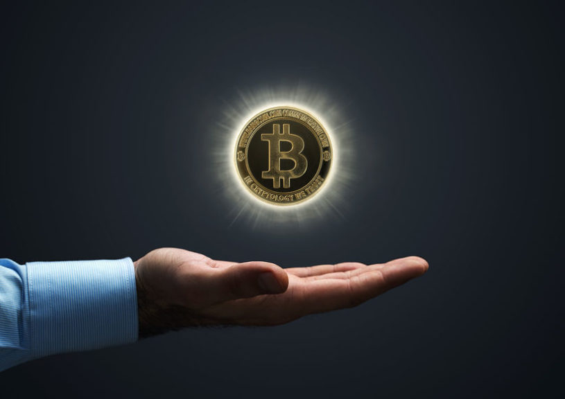Business man's hand with palm extended and a gravitating Bitcoin floating above his hand.