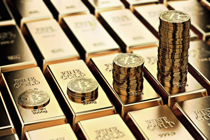 Several gold bullions with Bitcoin tokens stacked on top of them.