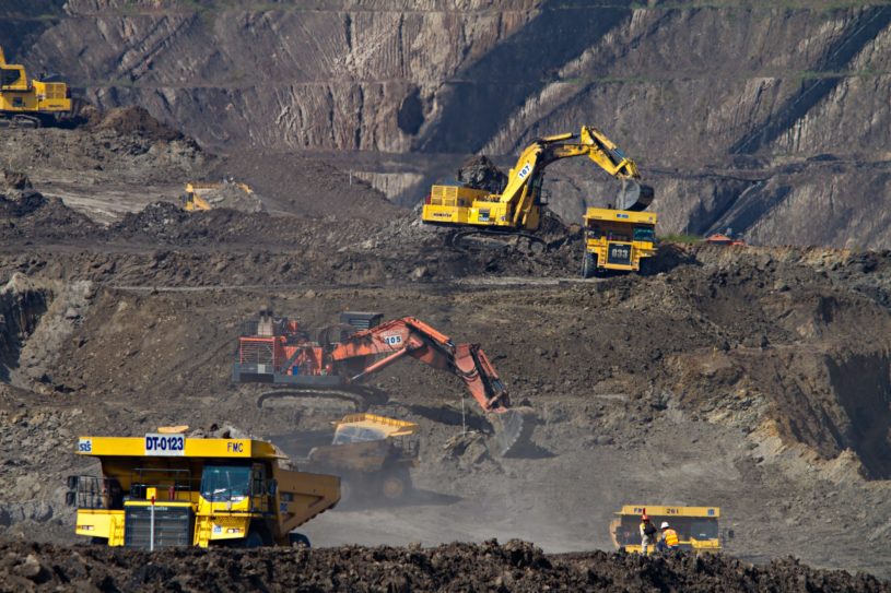 Trucks and heavy equipment working in a mine to mine gold, silver, and copper