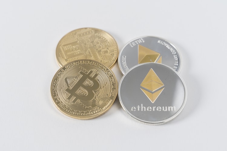Two coins on a white background, one representing Bitcoin and other Ethereum.