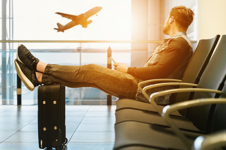 A casually dressed man comfortably waits for airplane departure.