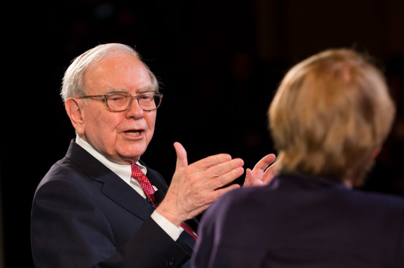 Billionaire Warren Buffett being interviewed in a dark room.