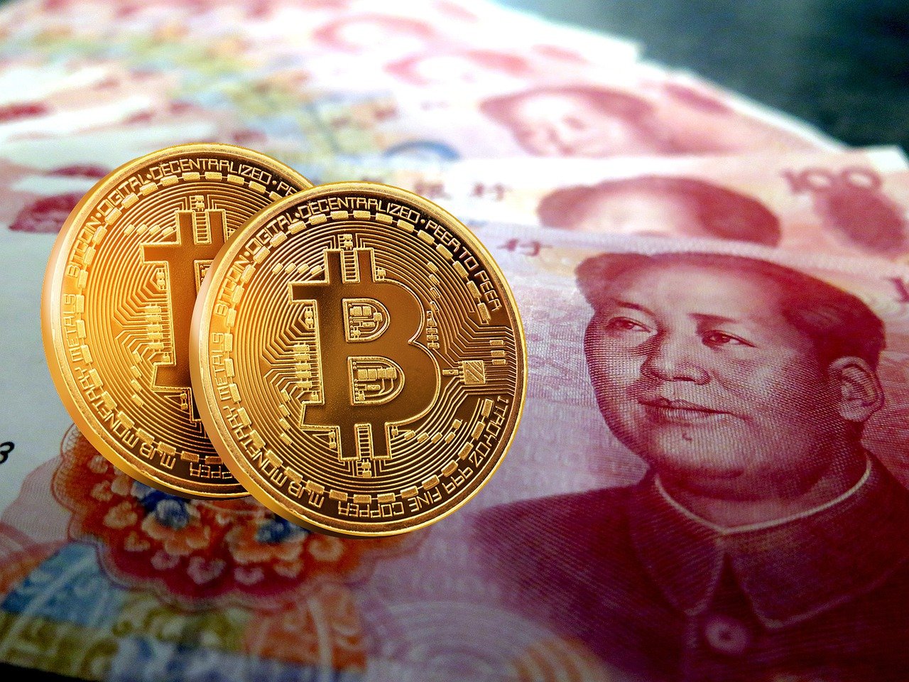 One hundred yuan banknotes, next to an e-RMB gold coin, digital version of the yuan.