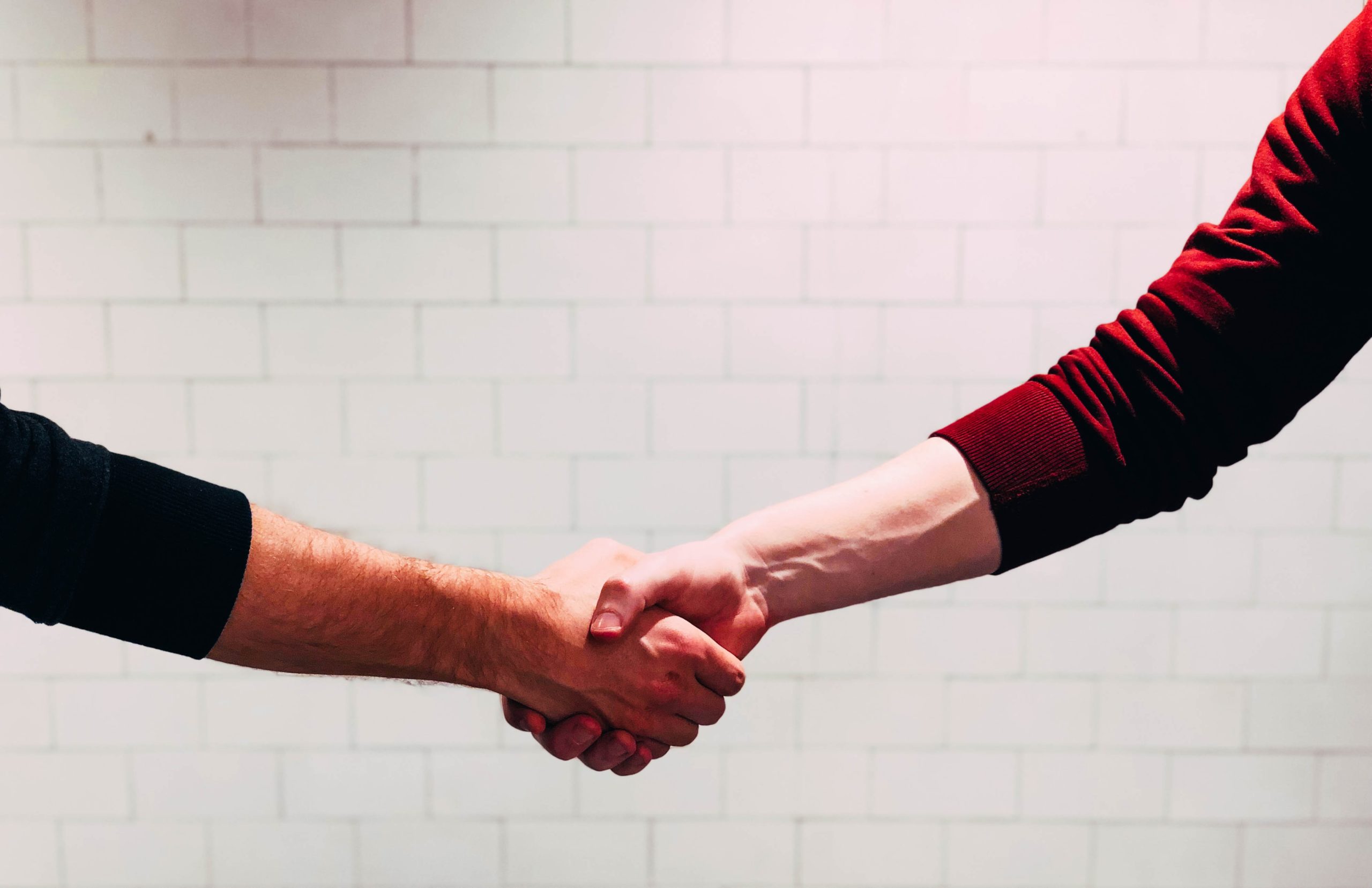 A black-clad hand shaking a red-clad hand.