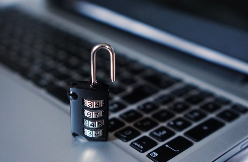 An unlocked number padlock is kept on a laptop keyboard.