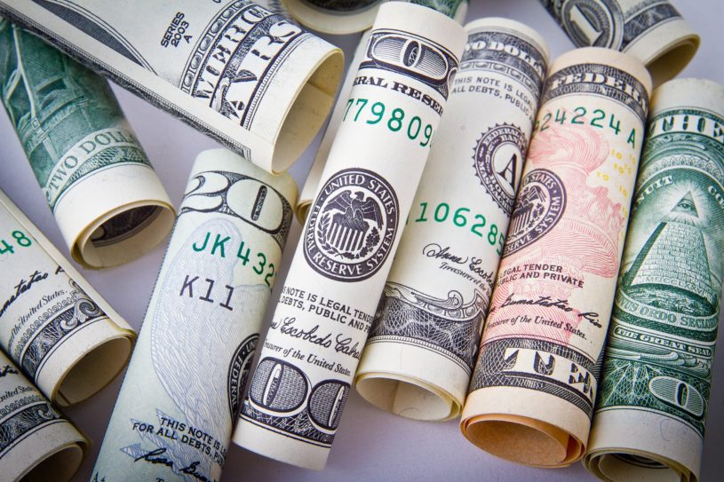 Different denomination US dollar bills rolled and stacked up.