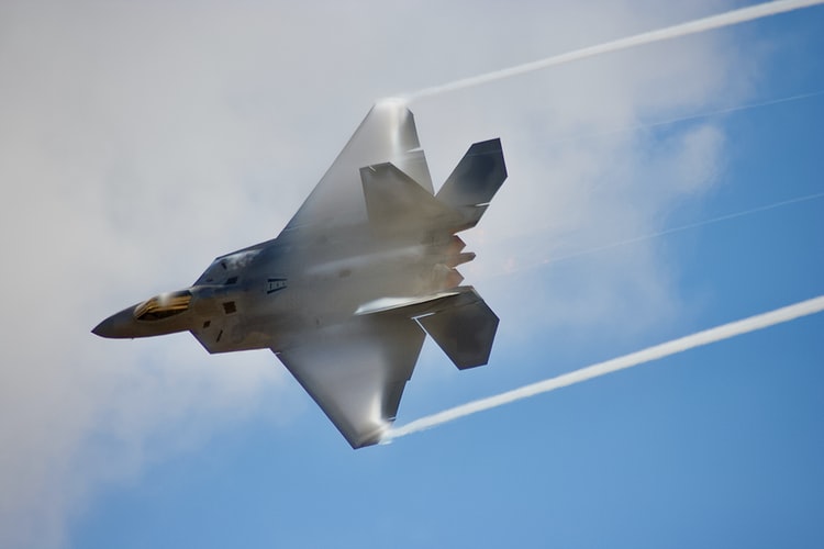 F-22 Raptor flying across clear blue sky