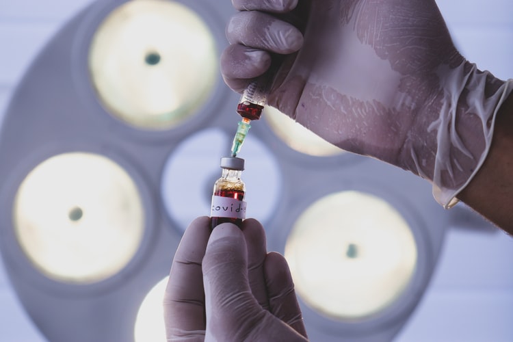 Medial technician handling a vial in a harshly lit room.