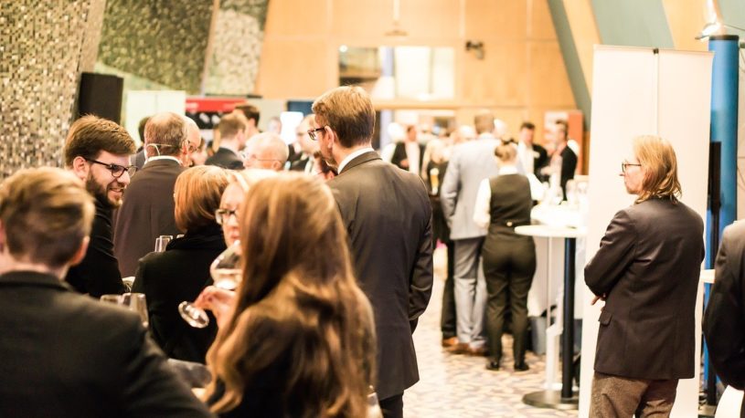 Group of business men and business women wearing business dress attending a digital assets conference and socializing.