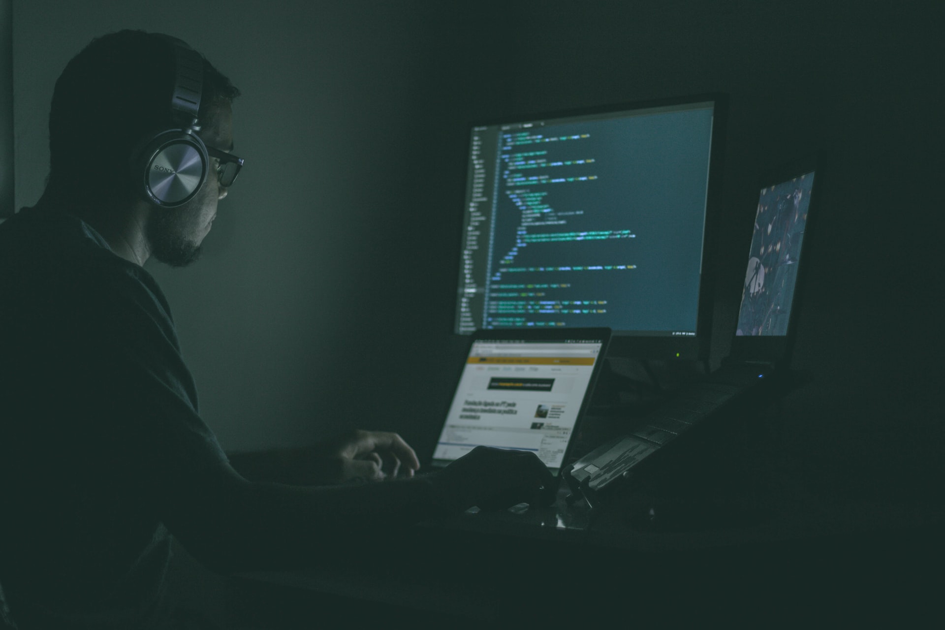 Hacker sitting in the dark and working on computer to hack databases