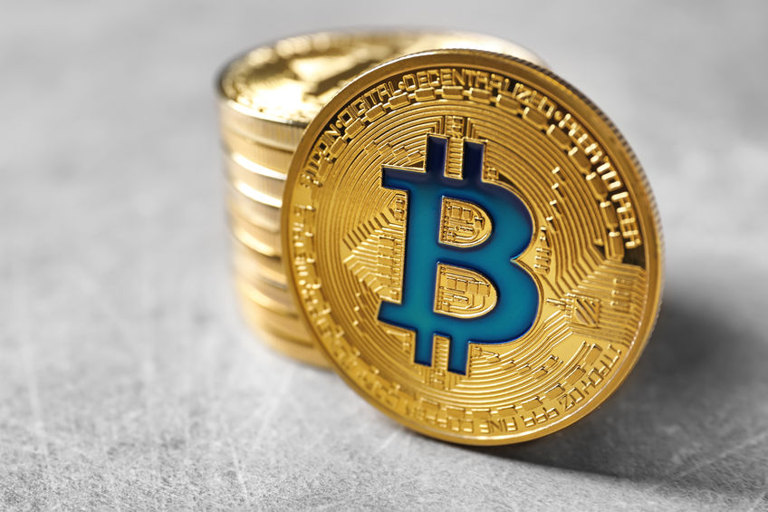 Several gold bitcoin tokens stacked on top of each other.