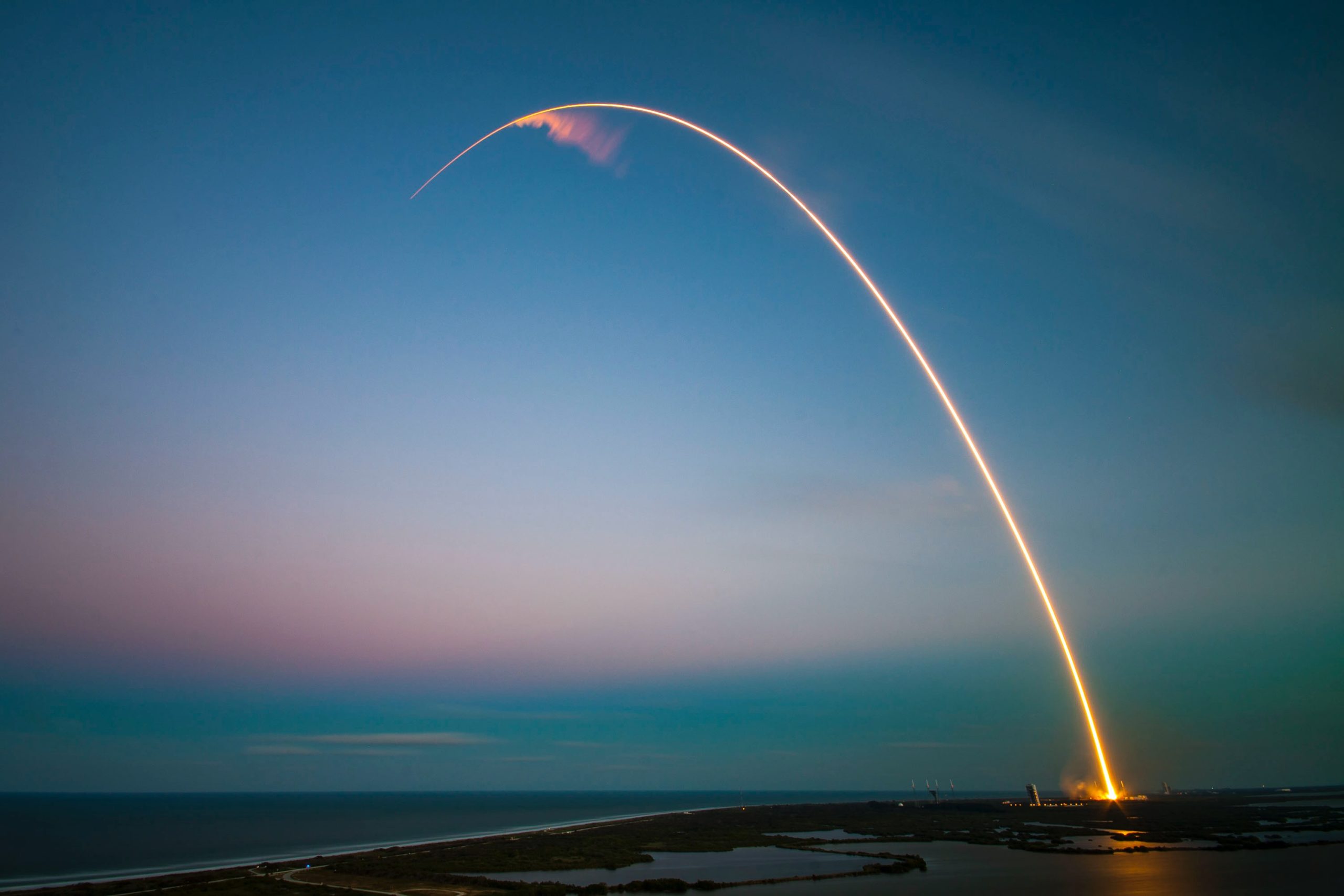 Rocket swooshing over a body of water, leaving a trail.