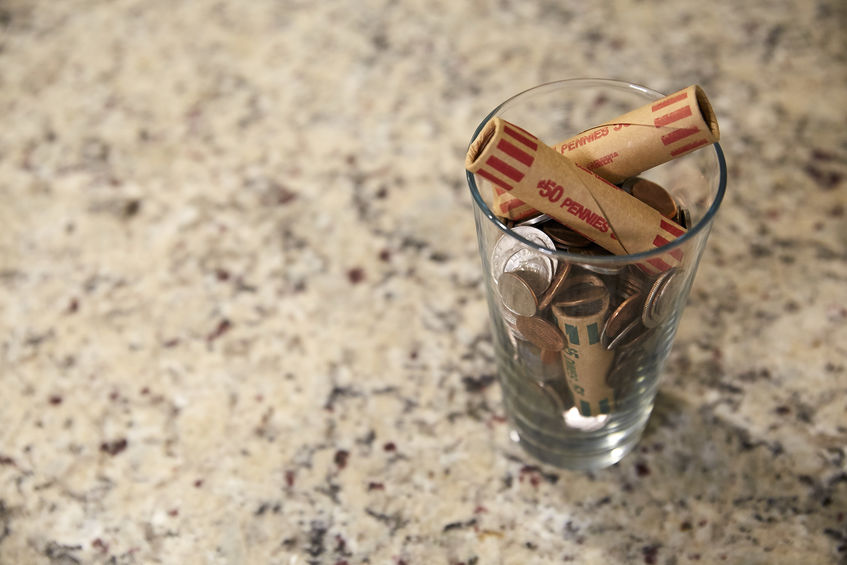 Glass jar on a counter top with pennies inside