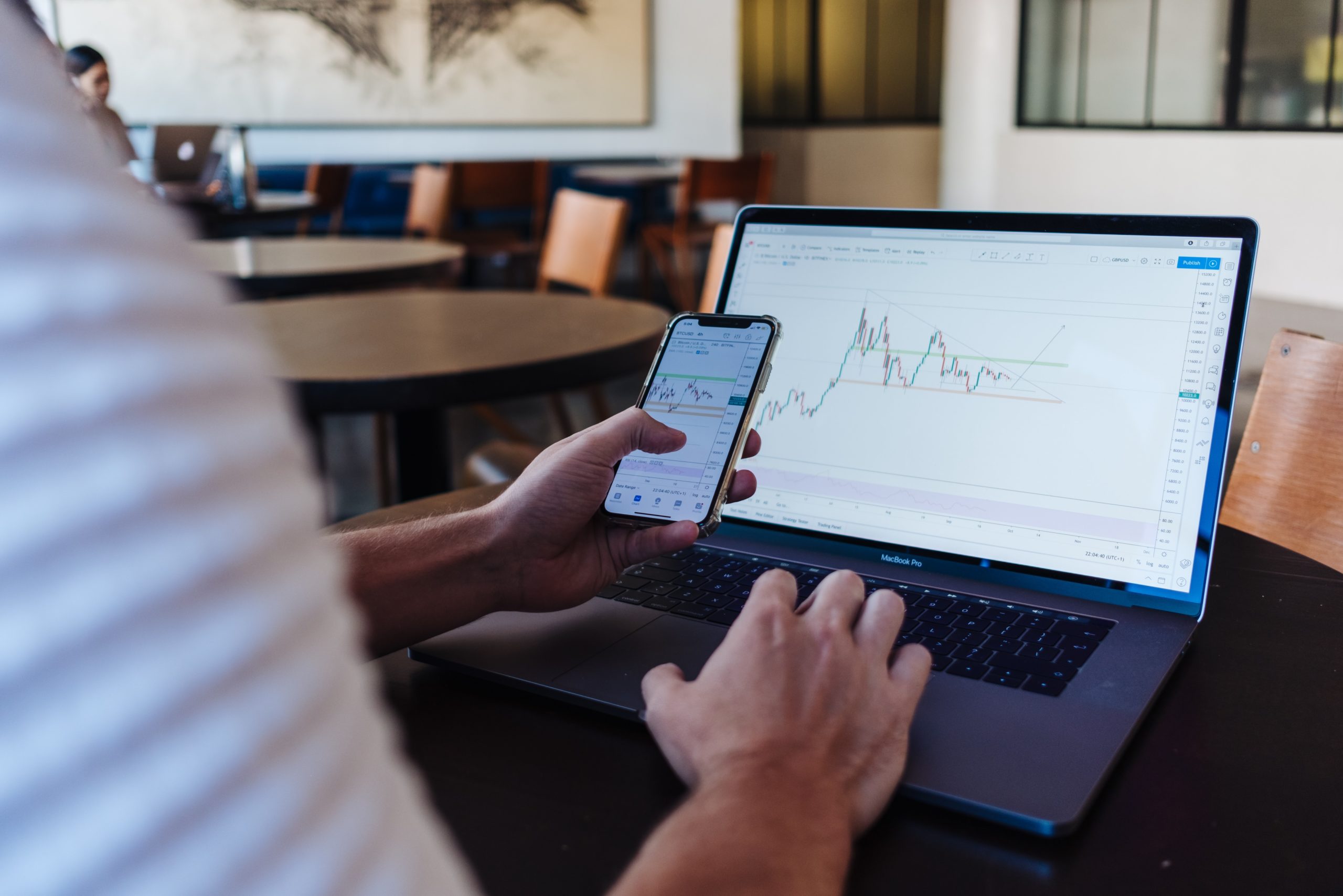 Financial candlestick charts on laptop and smartphone displaying the growth of NFTs.
