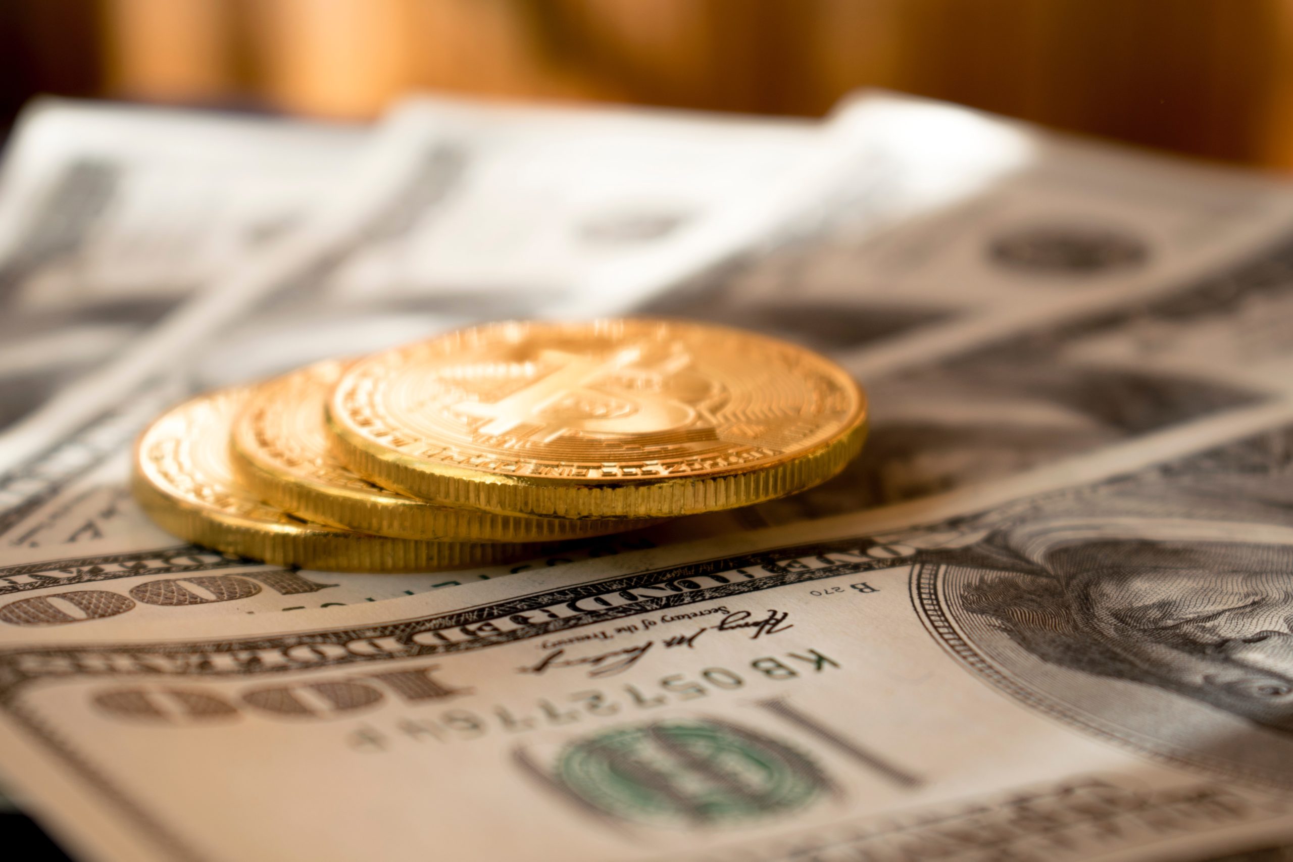 Golden tokens sitting on $100 USD notes.