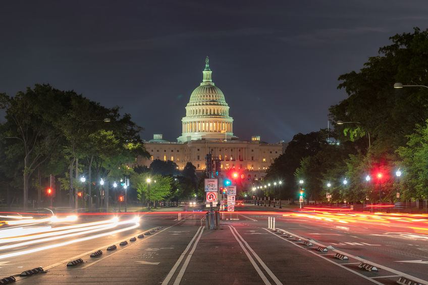 U.S. Capital Building at night, with empty streets and red street lights in the foreground.