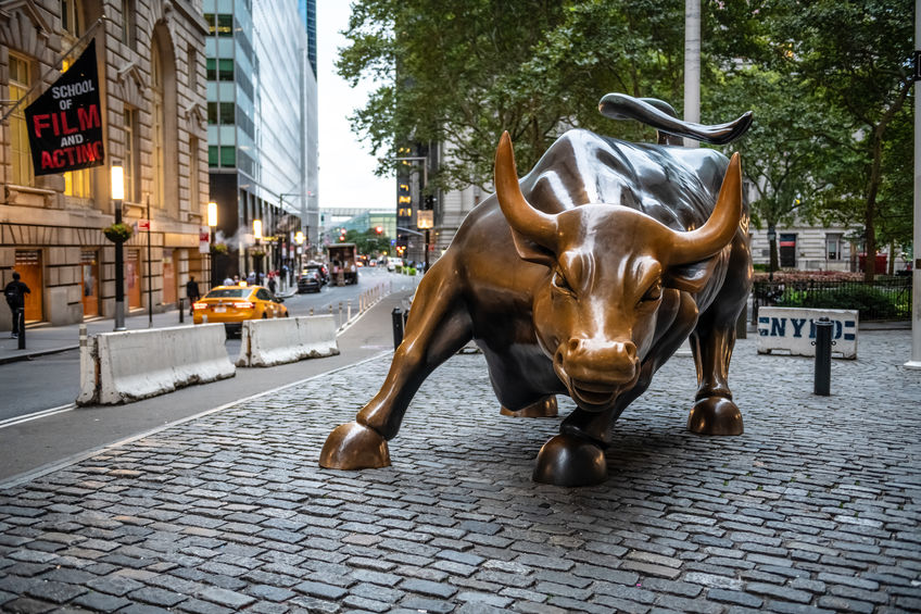 Wall Street bull bronze statue with green tree in background