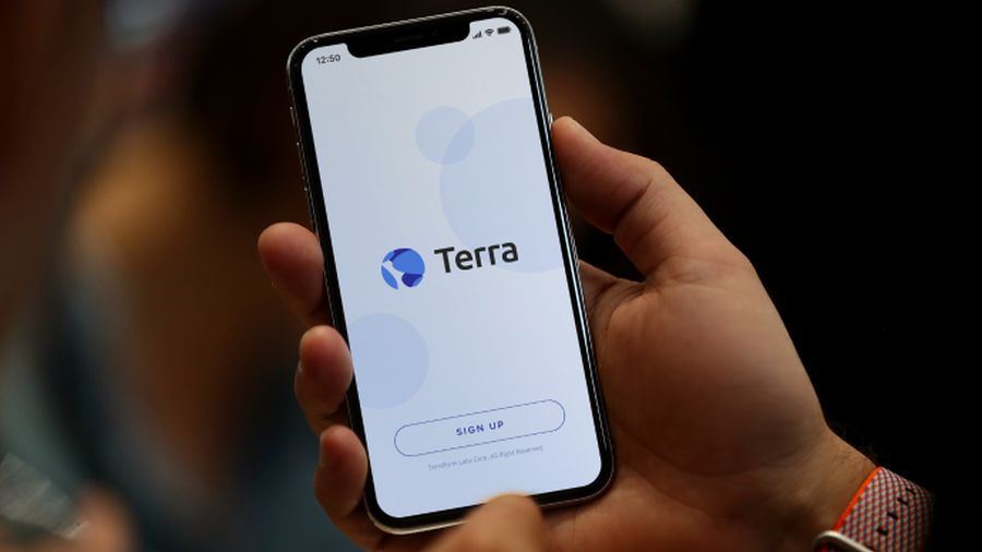 Person holding a smartphone with the Terra app open.