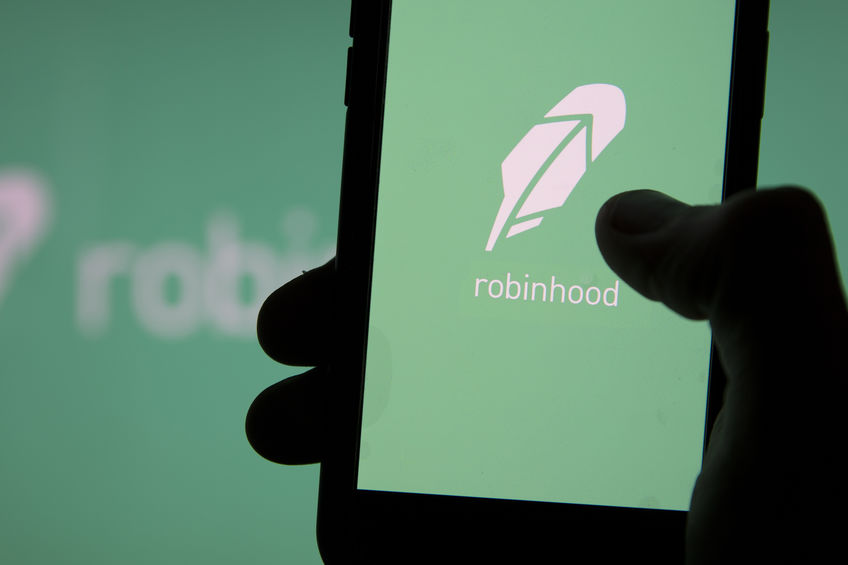 Millennial stock trader holding a cell phone with the Robinhood trading app open and a dark background