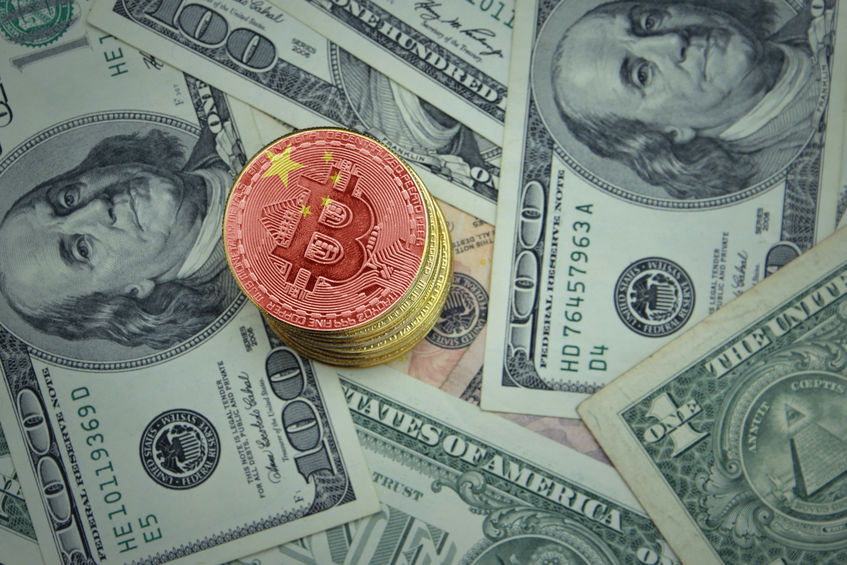 This image shows Bitcoin with a Chinese flag on it on a stack of U.S. dollars to symbolize how the two global entities have the power to manipulate the Bitcoin market