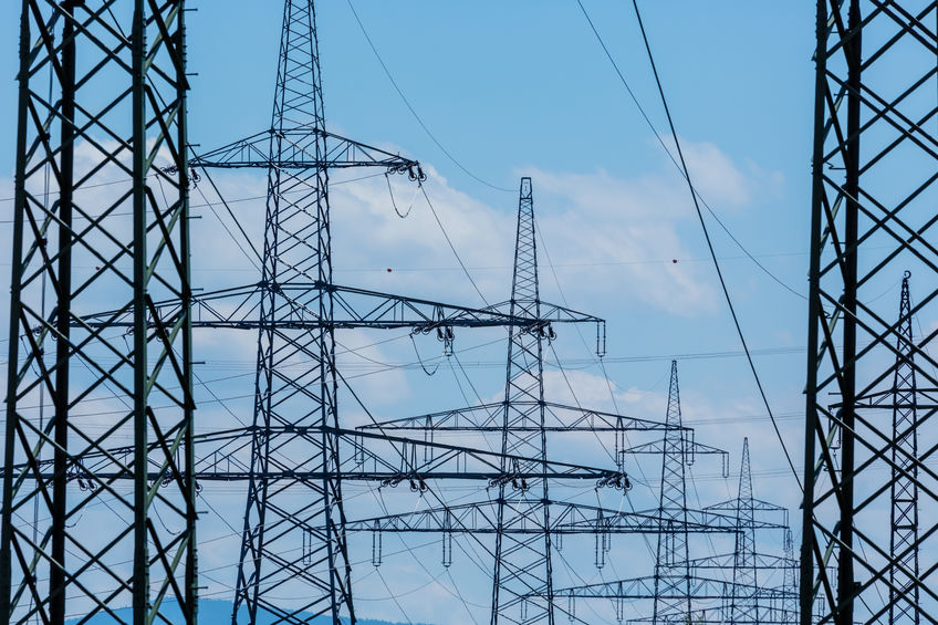 Lines of massive electricity poles with blue sky in the background, signifying the massive amount of electricity used in traditional banking vs Bitcoin.