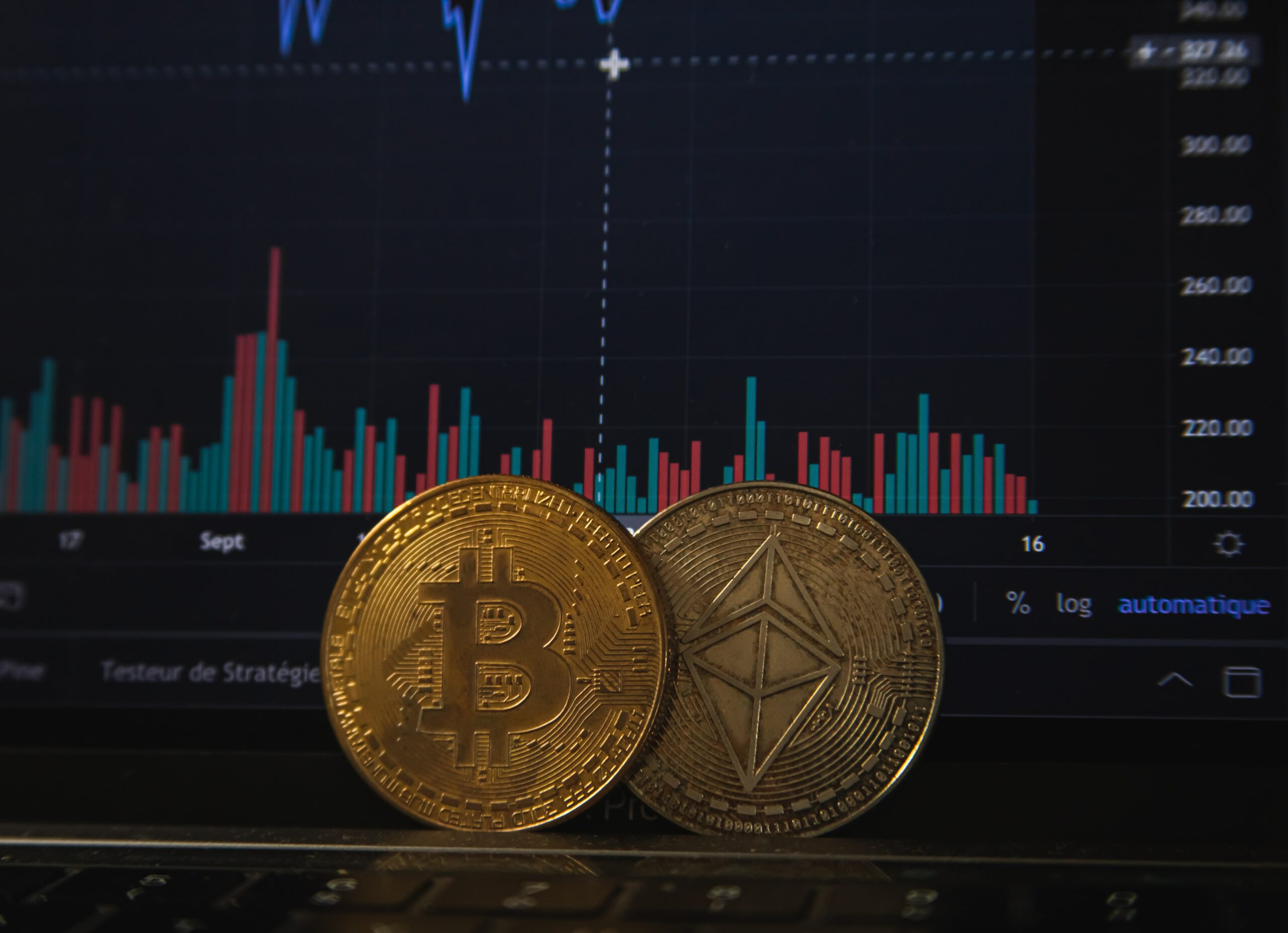 Ethereum and Bitcoin tokens next to each other with a financial candlestick chart in the background.