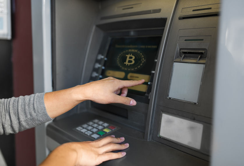 finance, cryptocurrency and technology concept - close up of woman at atm machine with bitcoin icon on screen