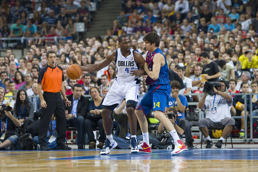 Dallas Mavericks team playing a basketball game in a crowded arena.