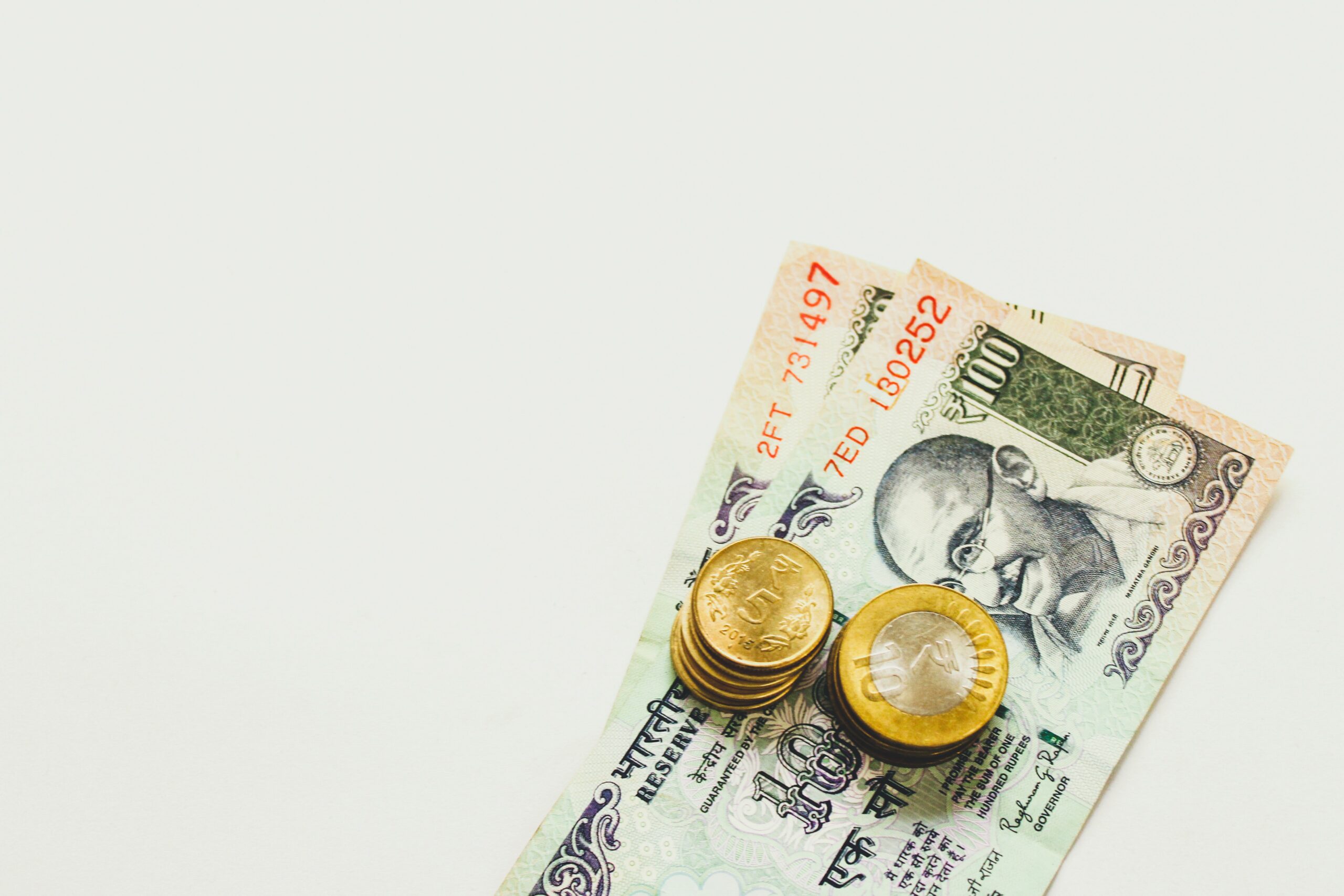 Indian currency - paper notes - on a table with coins stacked on top of them.