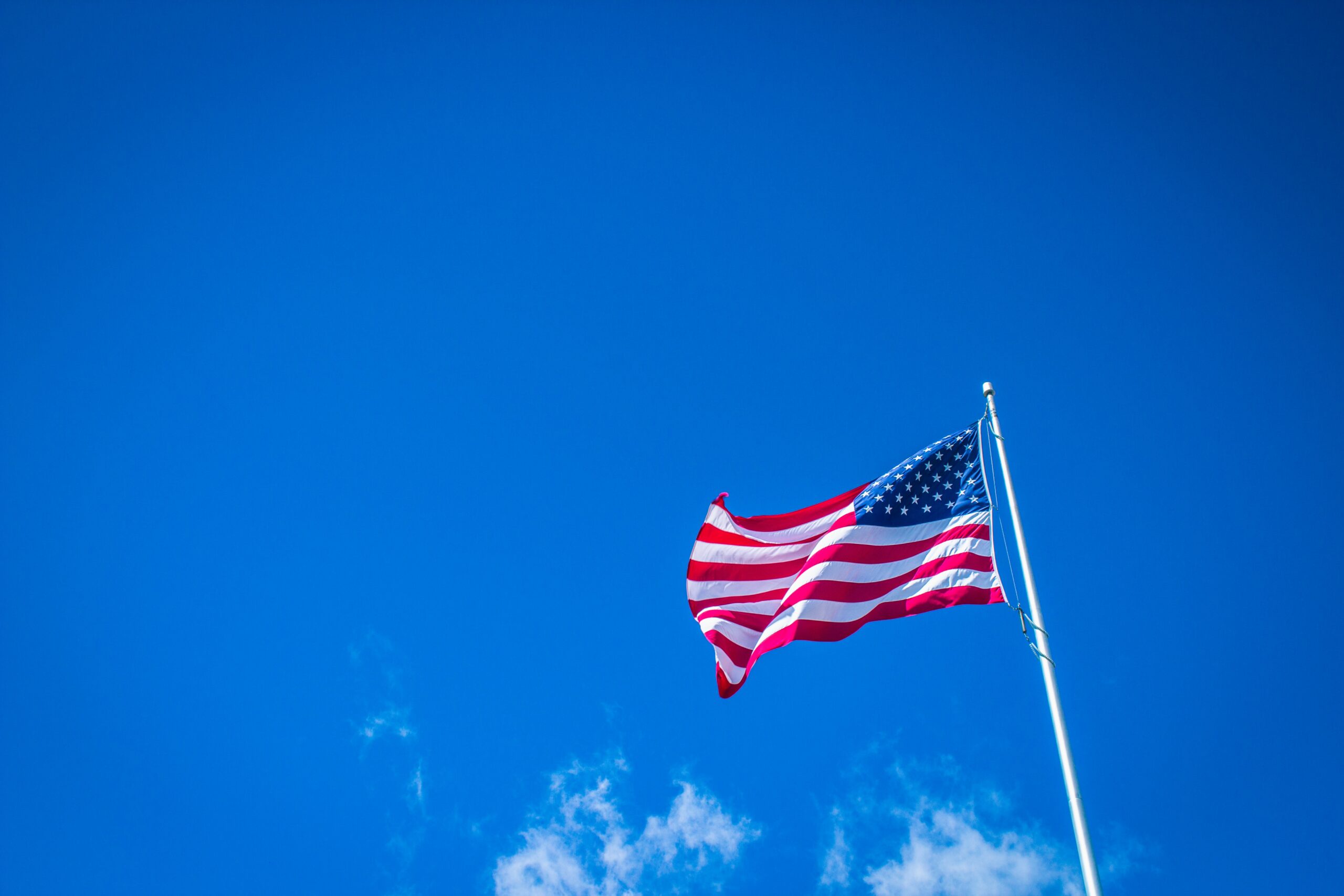 Blue sky in the background with an American flag waving in the wind.