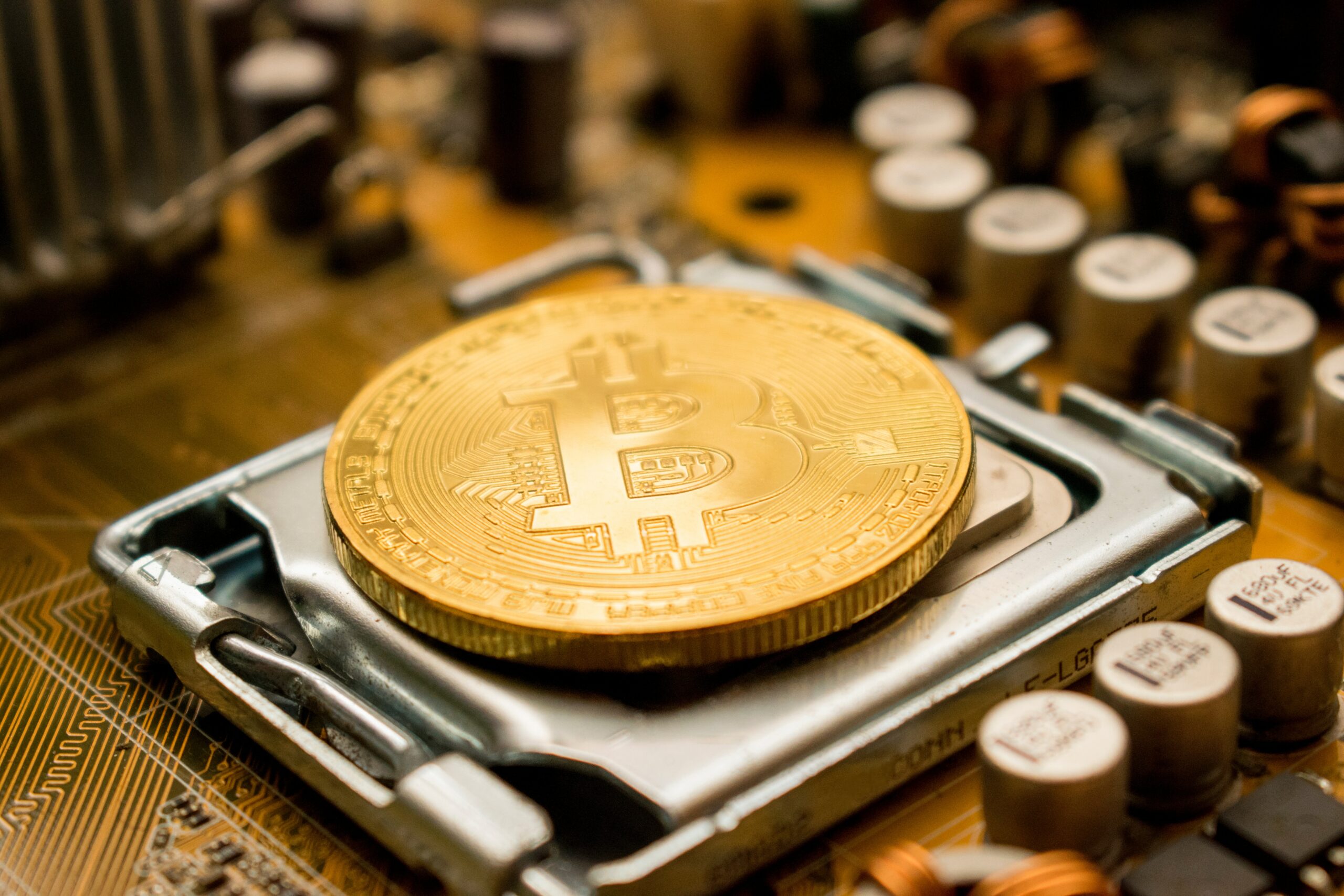 Image of a physical Bitcoin laying on computer parts, visualising the process of Bitcoin mining