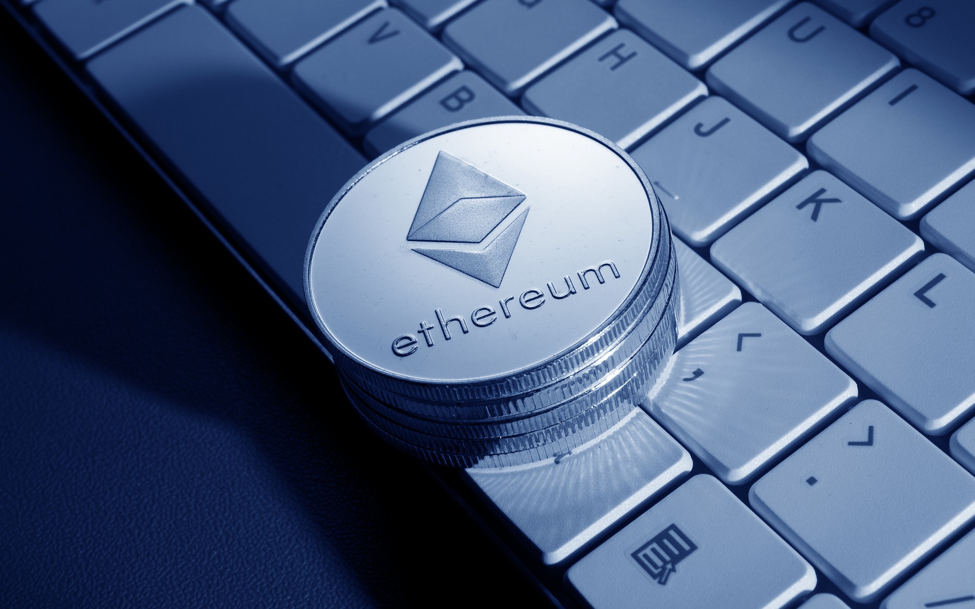 Ethereum coin sitting on a laptop keyboard.