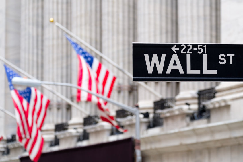 Wall street sign with the New York Stock Exchange and american flags on the background