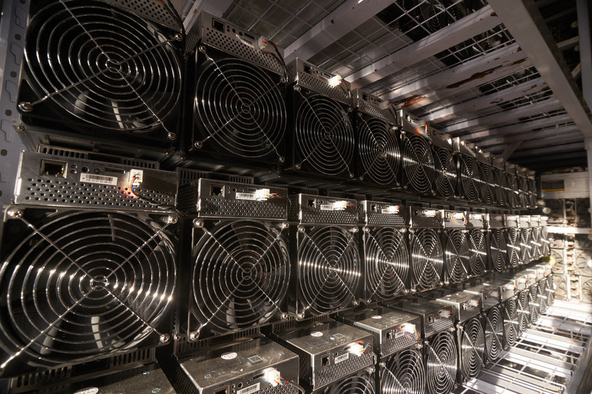 Bitcoin ASIC miners in warehouse. ASIC mining equipment on stand racks for mining cryptocurrency in steel container. Blockchain techology application specific integrated circuit storage.