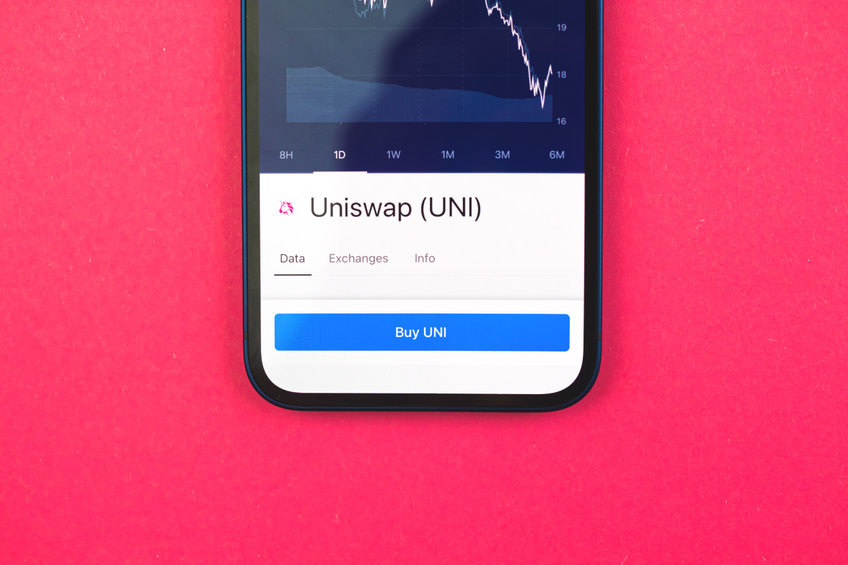 Buy Uniswap UNI crypto currency, mobile phone app with button, concept of online trade, investment and coin exchange with smartphone, finance, office desk top view photo.