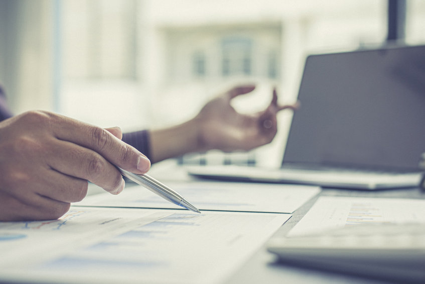 Pair of hands with a pen and some charts at a desk