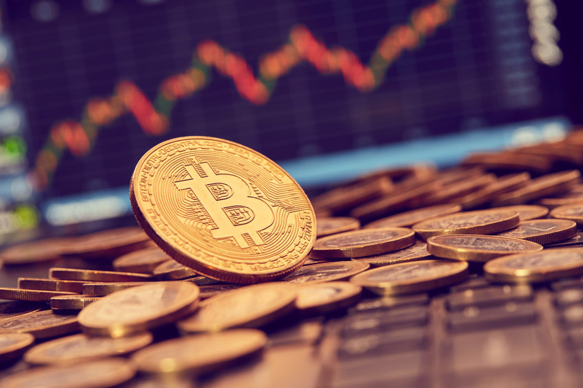 Image of Bitcoin on a keyboard with charts in the background