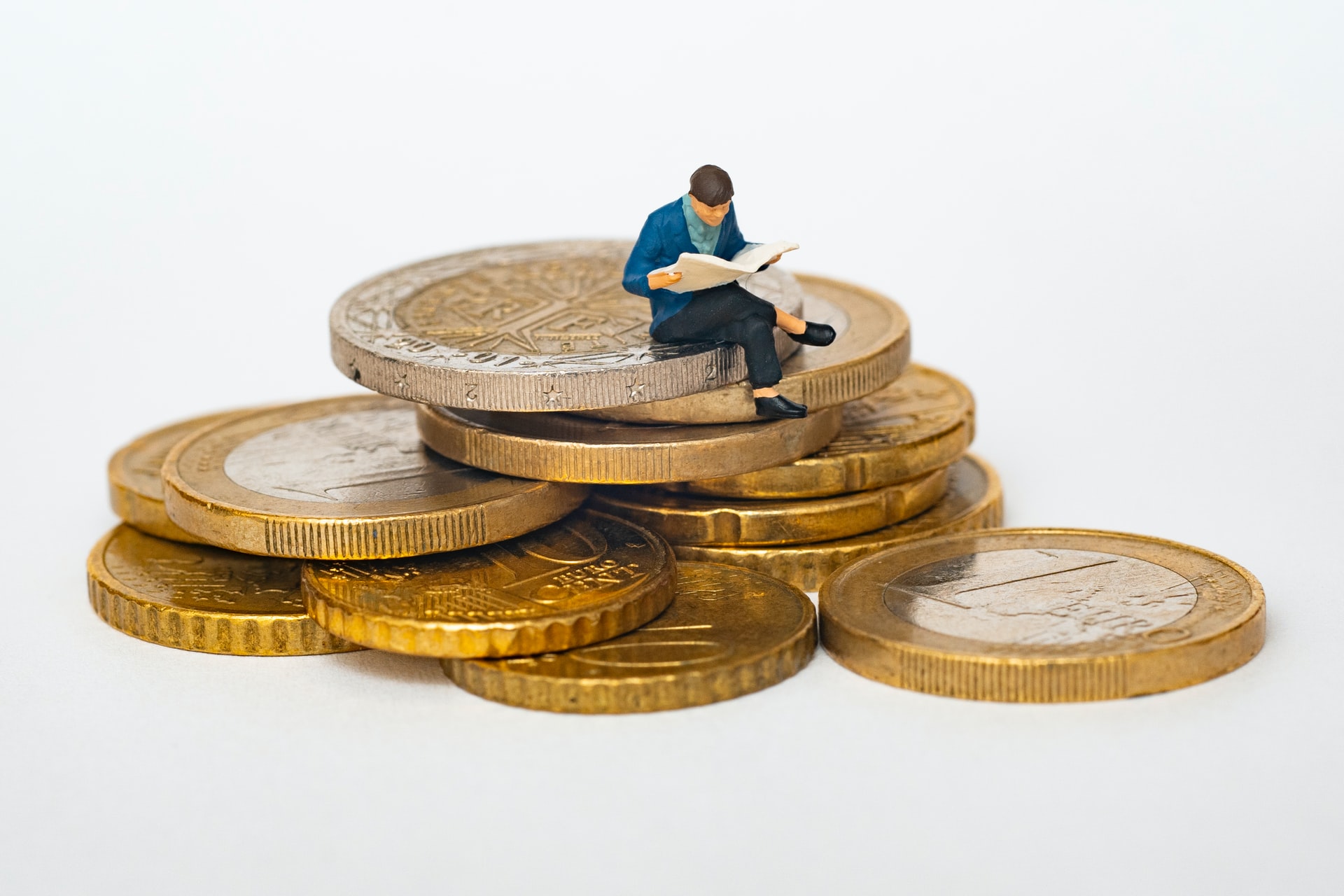Image of a small man sitting on a pile of coins