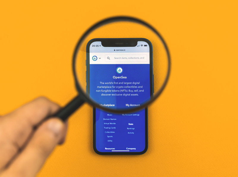 Image of the OpenSea mobile app under a magnifying glass